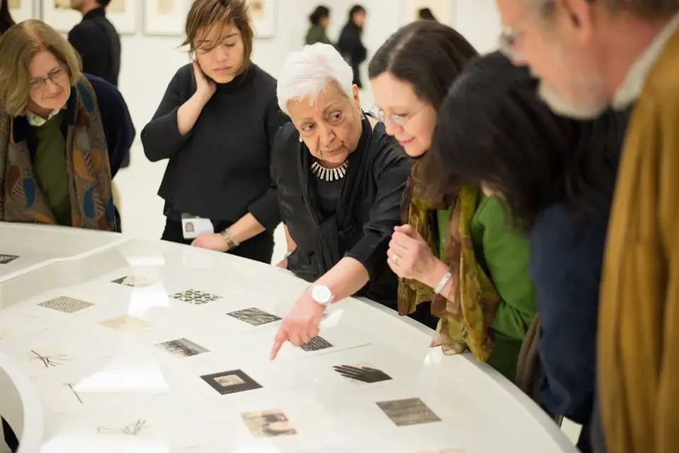 Zarina and visitors looking closely at works on paper